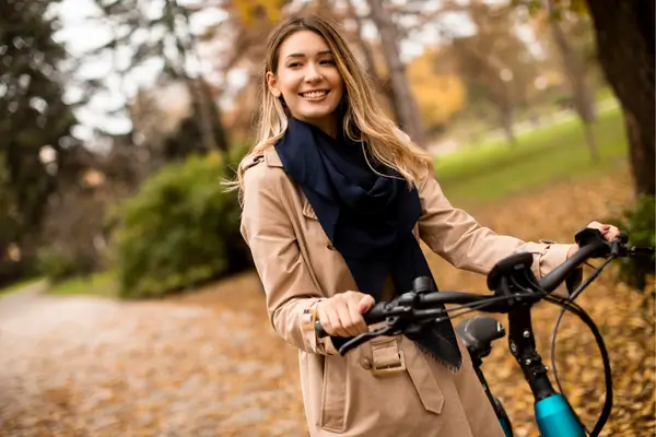 Protagonista de dorama sorrindo ao pedalar sua bicicleta em um caminho arborizado, encontrando beleza no caminho.